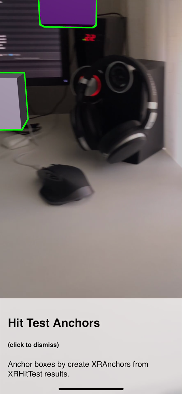 Two of the anchors seen past a headset on the desk, holding their place in the scene